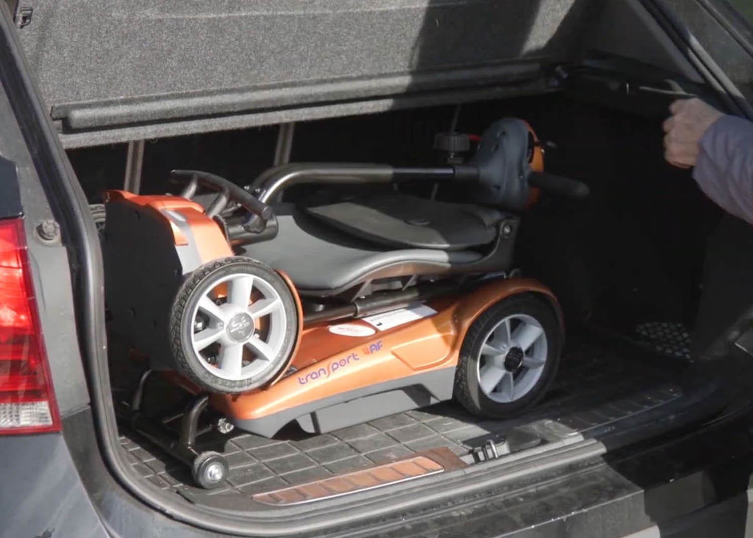 Transport4AF-012-1024x731 A copper-colored EV Rider Transport AF automatic folding scooter neatly folded inside a car trunk, showcasing automatic portability.